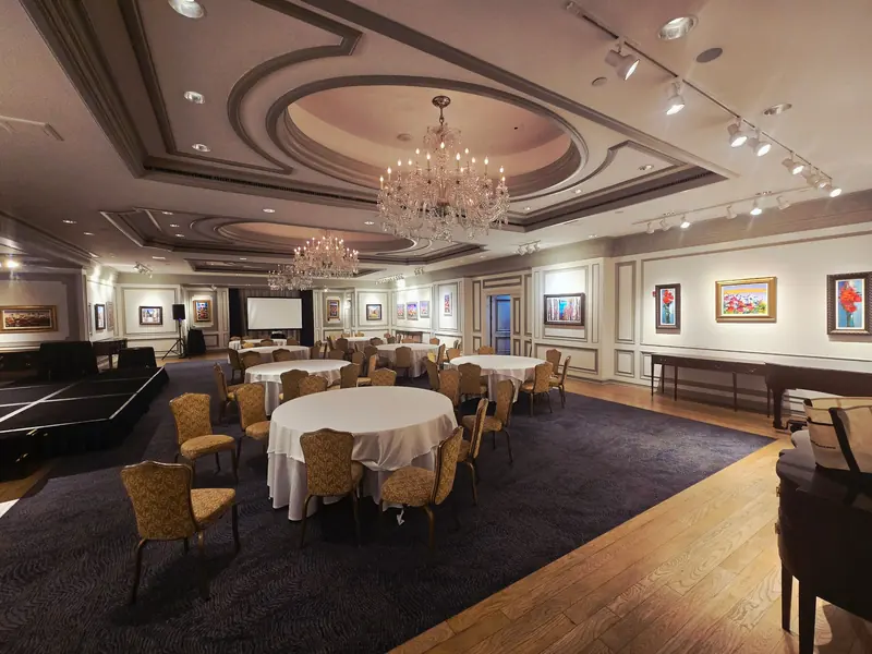 Ballroom with round tables, chandeliers and a small stage, set out for a meeting